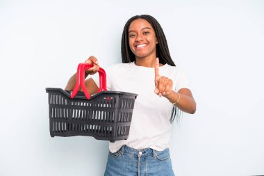 black pretty woman smiling proudly and confidently making number one. empty shopping basket