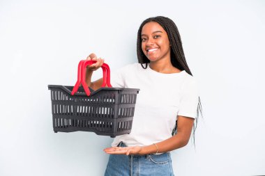 black pretty woman smiling cheerfully, feeling happy and showing a concept. empty shopping basket