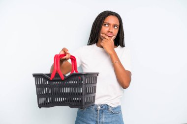 black pretty woman thinking, feeling doubtful and confused. empty shopping basket