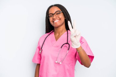 black pretty woman smiling and looking friendly, showing number two. nurse concept