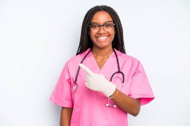 black pretty woman smiling cheerfully, feeling happy and pointing to the side. nurse concept