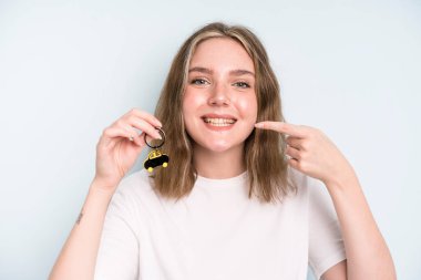 caucasian pretty woman smiling confidently pointing to own broad smile. new car concept