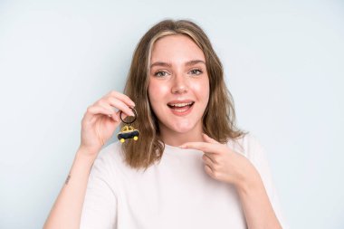 caucasian pretty woman looking excited and surprised pointing to the side. new car concept