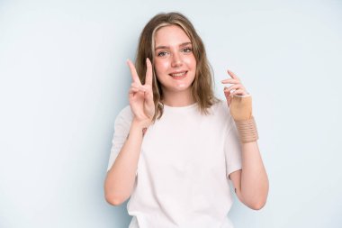 caucasian pretty woman smiling and looking happy, gesturing victory or peace. broken hand concept