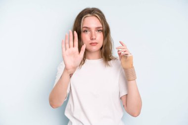 caucasian pretty woman looking serious showing open palm making stop gesture. broken hand concept