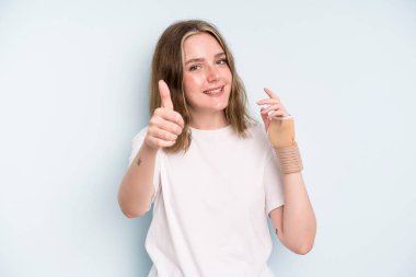 caucasian pretty woman feeling proud,smiling positively with thumbs up. broken hand concept