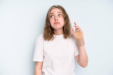 caucasian pretty woman shrugging, feeling confused and uncertain. broken hand concept