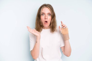 caucasian pretty woman looking surprised and shocked, with jaw dropped holding an object. broken hand concept