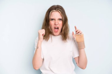 caucasian pretty woman shouting aggressively with an angry expression. broken hand concept