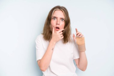 caucasian pretty woman with mouth and eyes wide open and hand on chin. broken hand concept