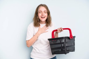 caucasian pretty woman laughing out loud at some hilarious joke. empty shopping basket concept
