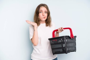 caucasian pretty woman feeling puzzled and confused and doubting. empty shopping basket concept