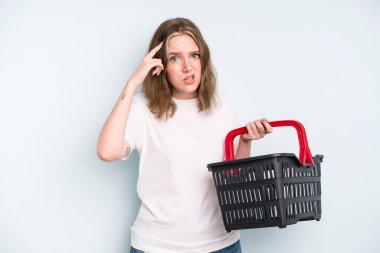 caucasian pretty woman feeling confused and puzzled, showing you are insane. empty shopping basket concept