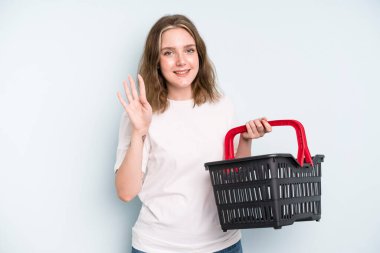 caucasian pretty woman smiling and looking friendly, showing number four. empty shopping basket concept