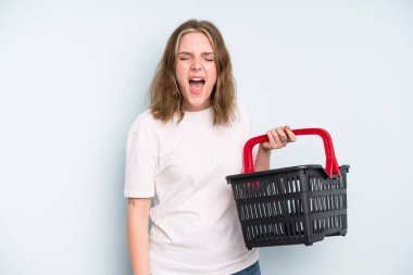 caucasian pretty woman shouting aggressively, looking very angry. empty shopping basket concept