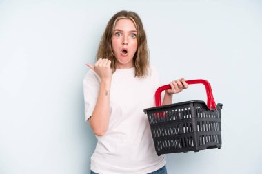 caucasian pretty woman looking astonished in disbelief. empty shopping basket concept