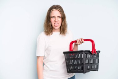caucasian pretty woman feeling disgusted and irritated and tongue out. empty shopping basket concept