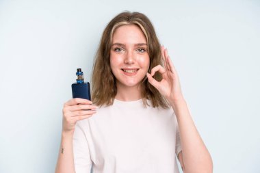 caucasian pretty woman feeling happy, showing approval with okay gesture. smoker with a vaper concept