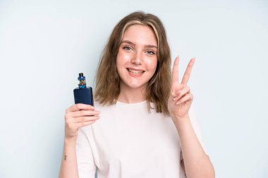 caucasian pretty woman smiling and looking happy, gesturing victory or peace. smoker with a vaper concept