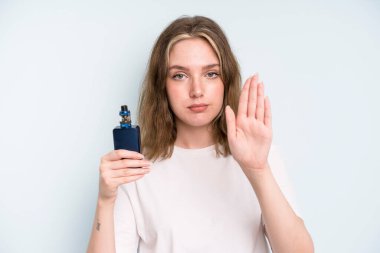 caucasian pretty woman looking serious showing open palm making stop gesture. smoker with a vaper concept