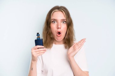 caucasian pretty woman looking surprised and shocked, with jaw dropped holding an object. smoker with a vaper concept