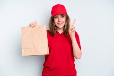 caucasian pretty woman smiling and looking happy, gesturing victory or peace. delivery and take away concept