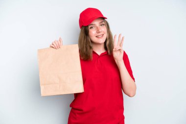 caucasian pretty woman smiling and looking friendly, showing number three. delivery and take away concept