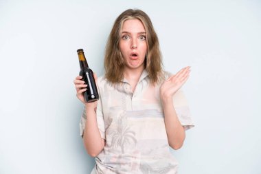 caucasian pretty woman looking surprised and shocked, with jaw dropped holding an object. beer concept