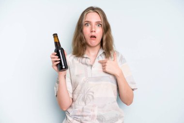 caucasian pretty woman looking shocked and surprised with mouth wide open, pointing to self. beer concept