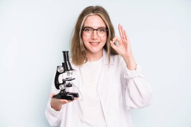 caucasian pretty woman feeling shocked,laughing and celebrating success. science student with a microscope