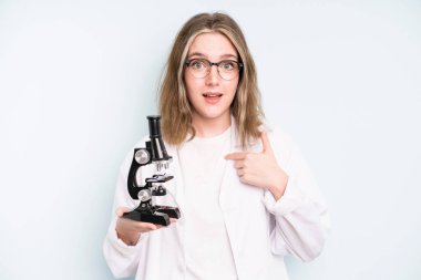 caucasian pretty woman looking very shocked or surprised. science student with a microscope