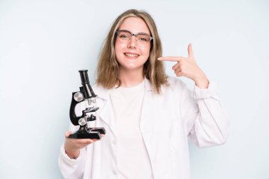 caucasian pretty woman making capice or money gesture, telling you to pay. science student with a microscope