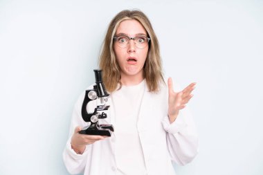 caucasian pretty woman shouting aggressively with an angry expression. science student with a microscope