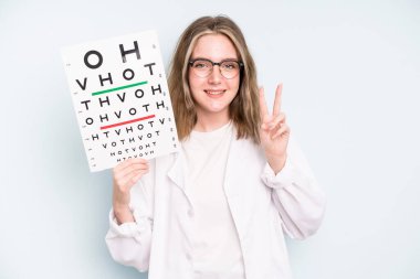 caucasian pretty woman smiling and looking friendly, showing number one. optical vision test concept