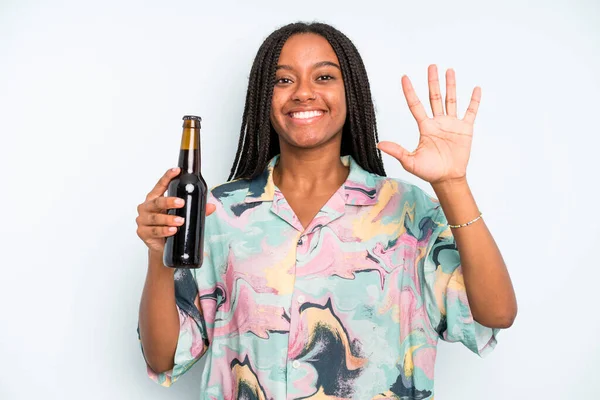 black pretty woman smiling and looking friendly, showing number five beer and holidays concept