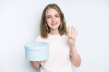 caucasian pretty woman smiling and looking friendly, showing number three. gift box concept