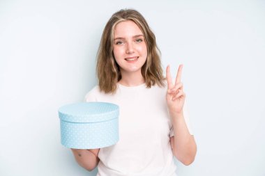 caucasian pretty woman smiling and looking friendly, showing number one. gift box concept