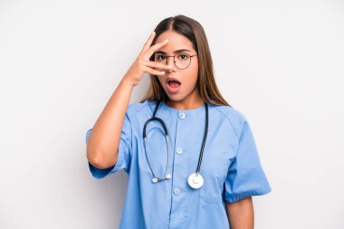 hispanic pretty woman looking shocked, scared or terrified, covering face with hand. medicine student concept