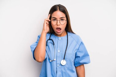hispanic pretty woman looking surprised, realizing a new thought, idea or concept. medicine student concept