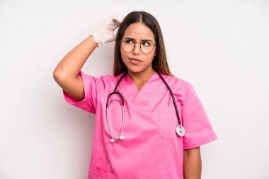hispanic pretty woman feeling puzzled and confused, scratching head. medicine student concept