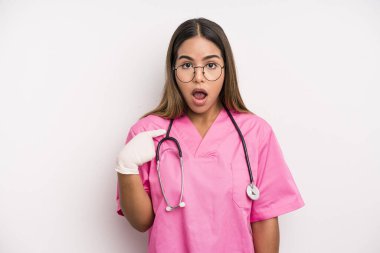 hispanic pretty woman looking shocked and surprised with mouth wide open, pointing to self. medicine student concept