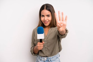 hispanic pretty woman smiling and looking friendly, showing number four. presenter with a microphone concept
