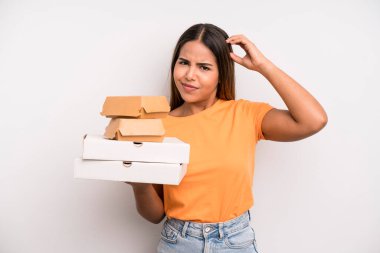 hispanic pretty woman feeling puzzled and confused, scratching head. fast food and take away concept