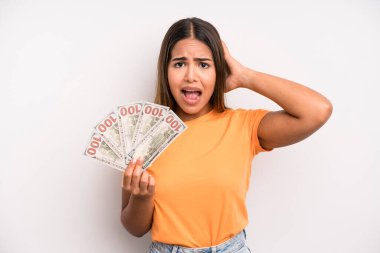 hispanic pretty woman feeling stressed, anxious or scared, with hands on head. dollar banknotes savings concept