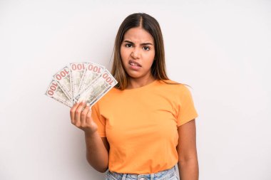 hispanic pretty woman feeling puzzled and confused. dollar banknotes savings concept