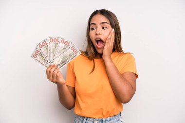 hispanic pretty woman feeling happy, excited and surprised. dollar banknotes savings concept