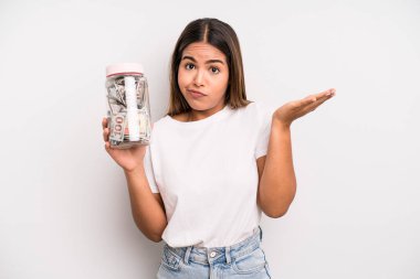 hispanic pretty woman feeling puzzled and confused and doubting. dollar banknotes savings concept