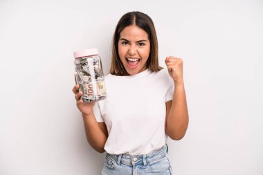 hispanic pretty woman feeling shocked,laughing and celebrating success. dollar banknotes savings concept