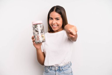 hispanic pretty woman pointing at camera choosing you. dollar banknotes savings concept