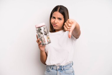 hispanic pretty woman feeling cross,showing thumbs down. dollar banknotes savings concept